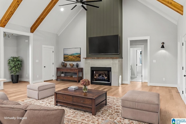 living room featuring ceiling fan, light hardwood / wood-style flooring, high vaulted ceiling, beamed ceiling, and a fireplace