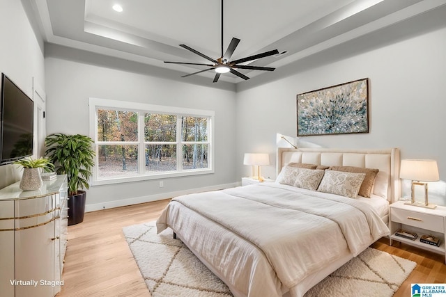 bedroom featuring a tray ceiling, ceiling fan, and light hardwood / wood-style floors