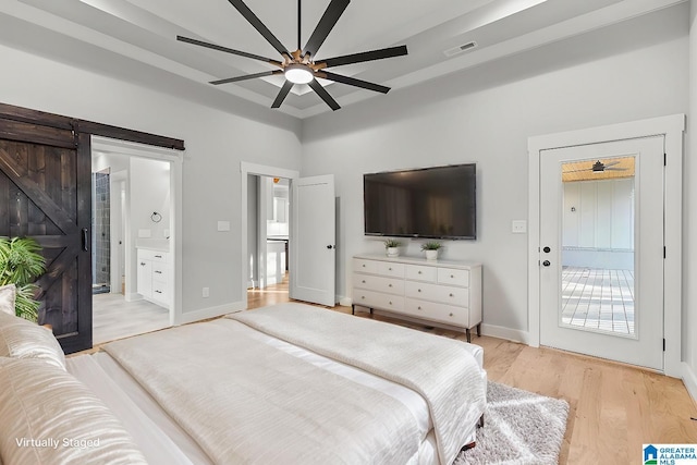 bedroom featuring connected bathroom, ceiling fan, a barn door, light hardwood / wood-style flooring, and access to outside