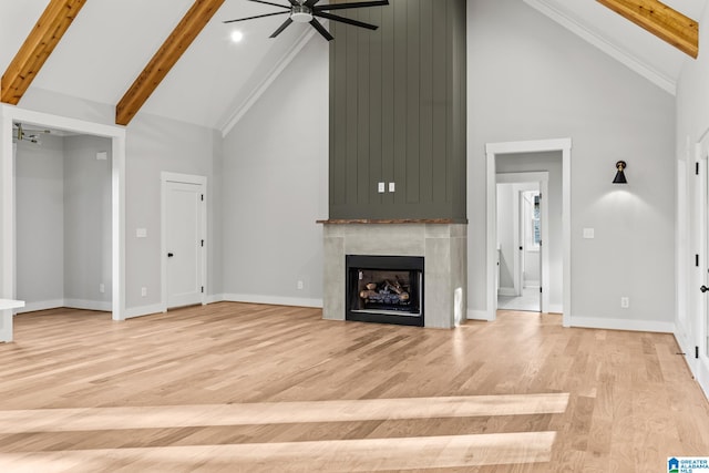 unfurnished living room featuring a large fireplace, ceiling fan, beam ceiling, light hardwood / wood-style flooring, and high vaulted ceiling