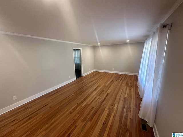 empty room with hardwood / wood-style floors and crown molding