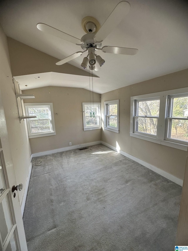 carpeted spare room with ceiling fan, plenty of natural light, and lofted ceiling