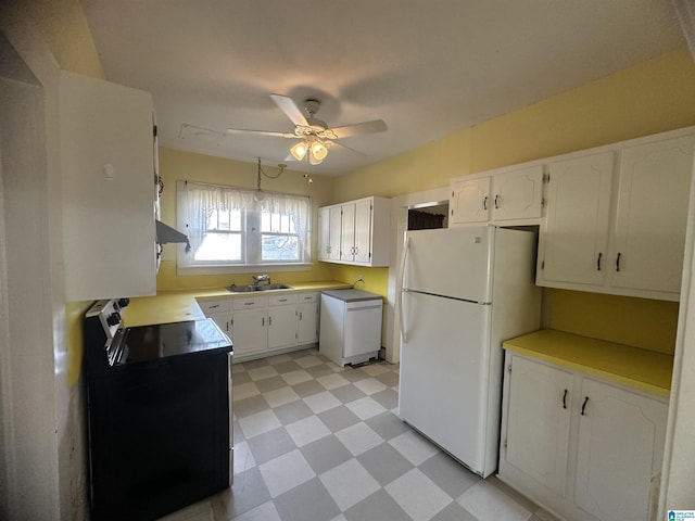 kitchen featuring ceiling fan, sink, black / electric stove, white fridge, and white cabinets