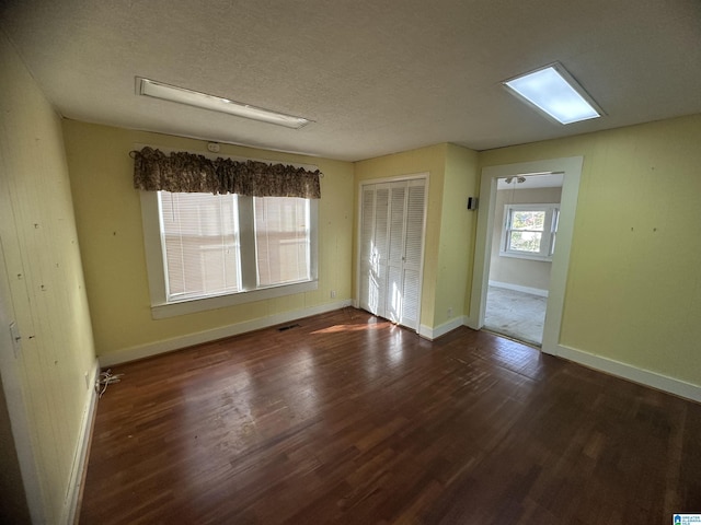 spare room featuring dark hardwood / wood-style floors and a textured ceiling