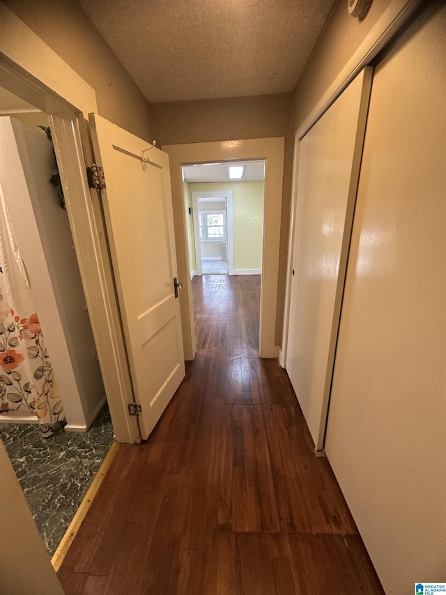 corridor featuring dark hardwood / wood-style flooring and a textured ceiling