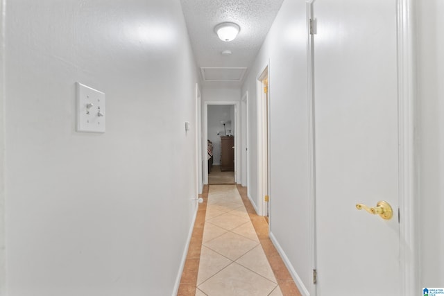 hall with a textured ceiling and light tile patterned floors