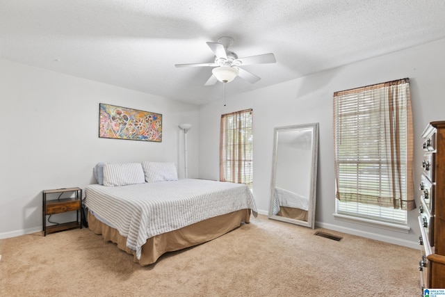 bedroom featuring a textured ceiling, light carpet, and ceiling fan