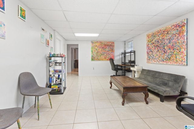 living room with a drop ceiling and light tile patterned floors