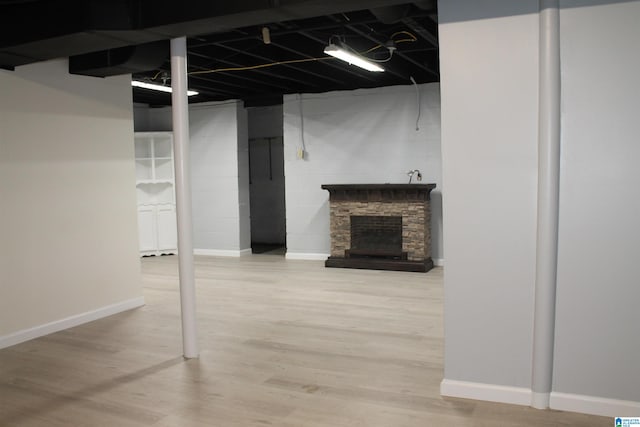 basement with hardwood / wood-style flooring and a stone fireplace