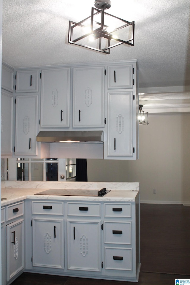 kitchen with a chandelier, light countertops, a textured ceiling, white cabinets, and black electric cooktop