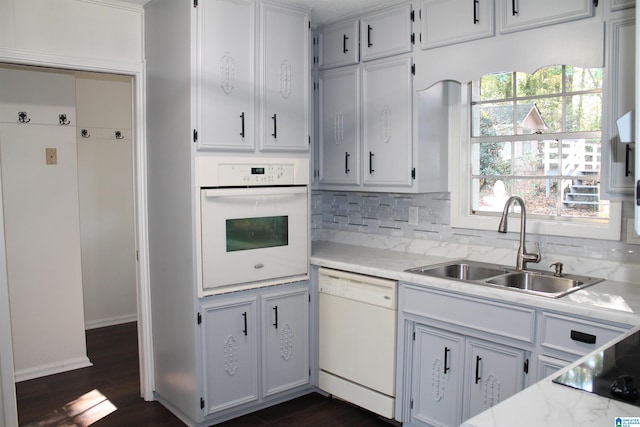 kitchen featuring white appliances, sink, decorative backsplash, dark hardwood / wood-style flooring, and white cabinetry