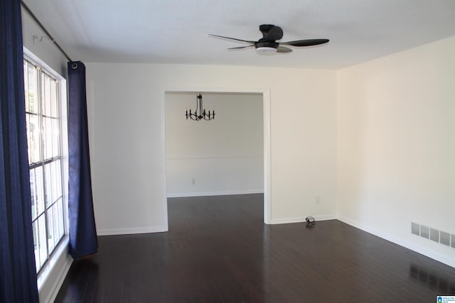 unfurnished room featuring dark wood-type flooring and ceiling fan with notable chandelier