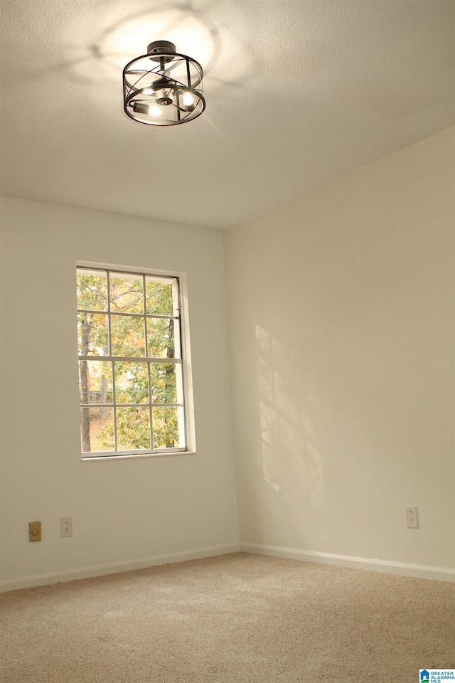 unfurnished room with carpet flooring, baseboards, and a textured ceiling