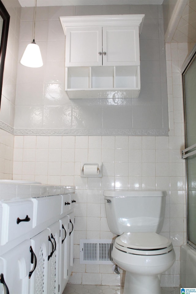 bathroom with tile walls, an enclosed shower, toilet, and tile patterned flooring