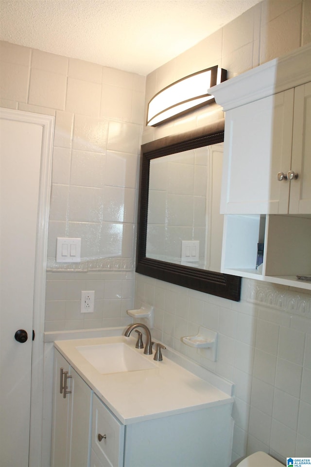 bathroom featuring tasteful backsplash, tile walls, vanity, and a textured ceiling