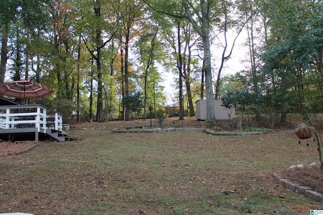 view of grassy yard with a shed, a deck, and an outdoor structure