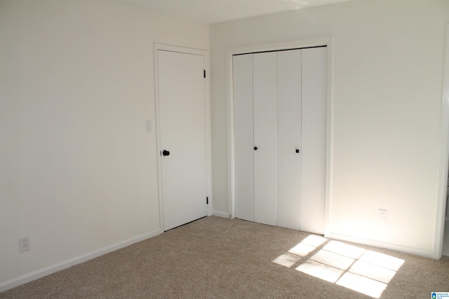 unfurnished bedroom featuring light carpet and a closet