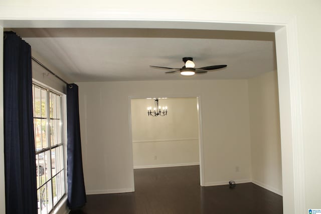 spare room with a chandelier, dark wood-style floors, baseboards, and a ceiling fan