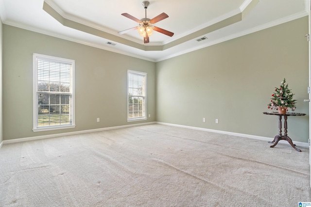 carpeted empty room featuring a raised ceiling, ceiling fan, and crown molding