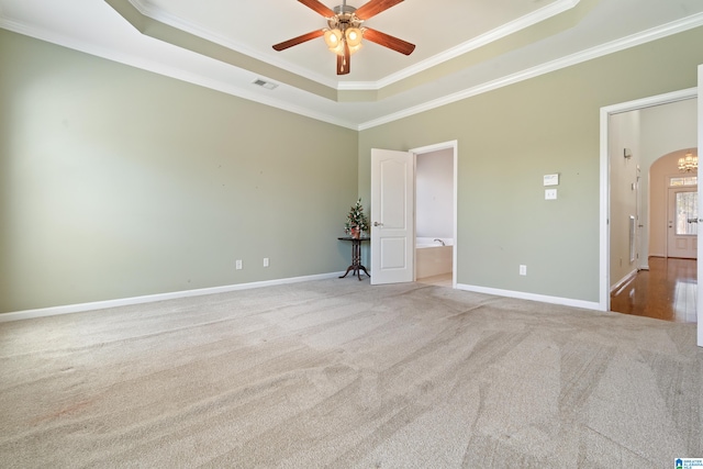 carpeted spare room with ceiling fan, a tray ceiling, and ornamental molding