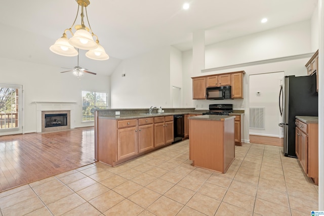 kitchen with light wood-type flooring, plenty of natural light, black appliances, and kitchen peninsula