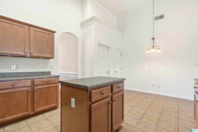 kitchen featuring pendant lighting, a towering ceiling, light tile patterned flooring, and a center island