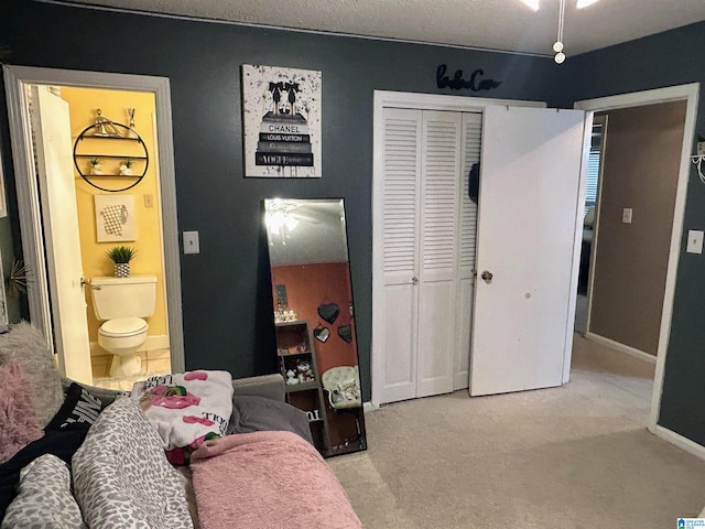 bedroom with light colored carpet, a textured ceiling, connected bathroom, and a closet