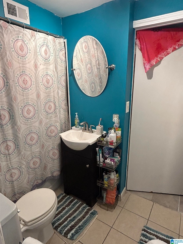 bathroom with toilet, vanity, and tile patterned floors