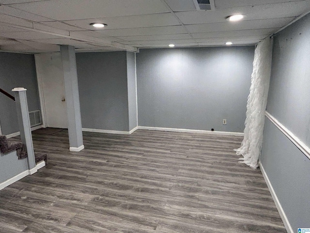 basement with a paneled ceiling and dark hardwood / wood-style floors