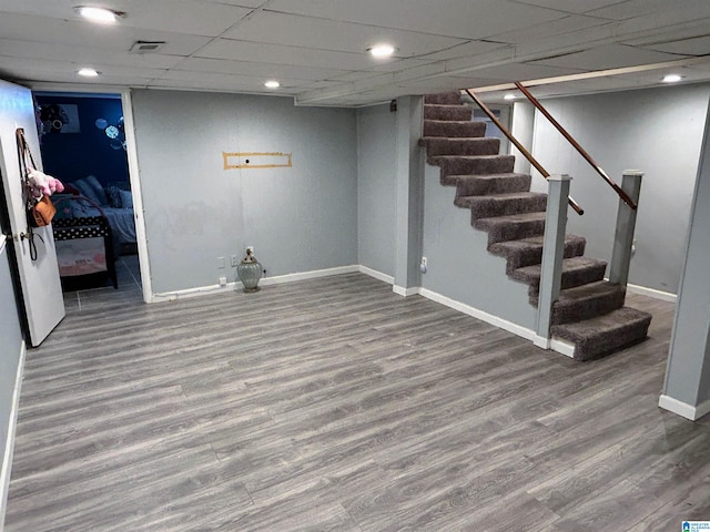 basement with a paneled ceiling and hardwood / wood-style flooring