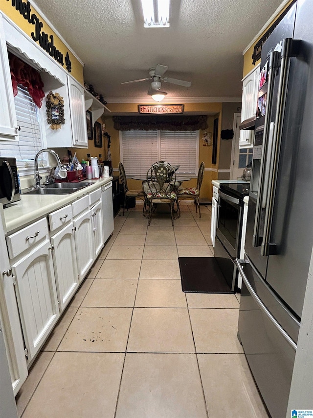 kitchen featuring light tile patterned floors, stainless steel appliances, white cabinetry, and sink