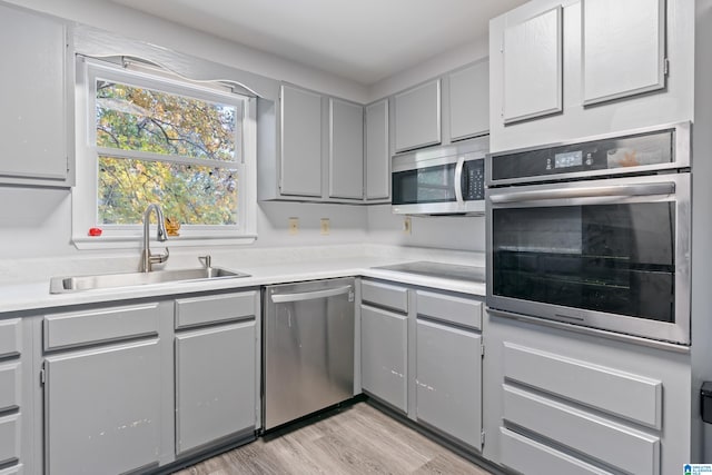 kitchen featuring gray cabinets, sink, appliances with stainless steel finishes, and light hardwood / wood-style flooring