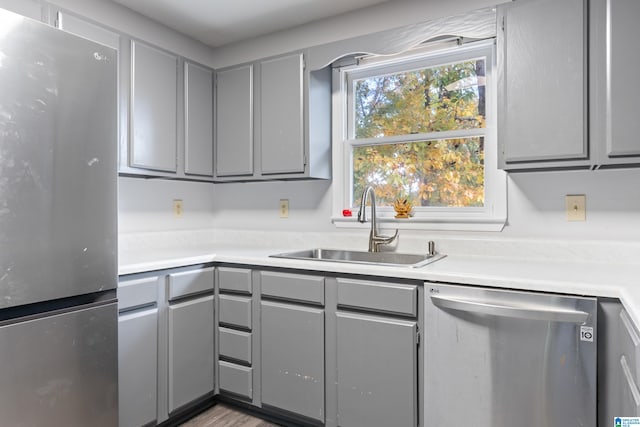 kitchen with gray cabinetry, sink, and stainless steel appliances