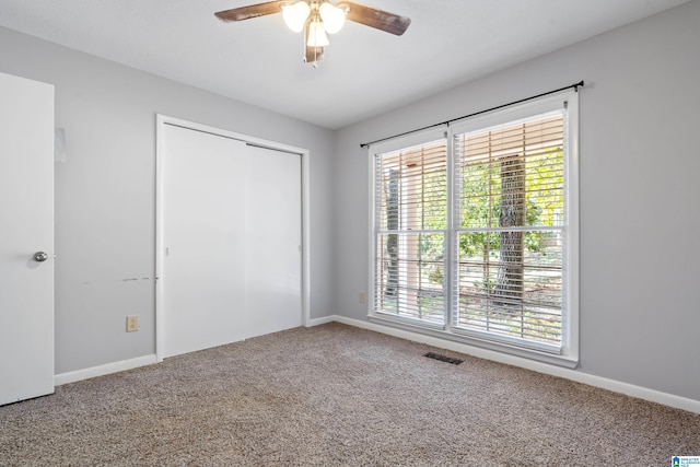 unfurnished bedroom featuring multiple windows, ceiling fan, and carpet