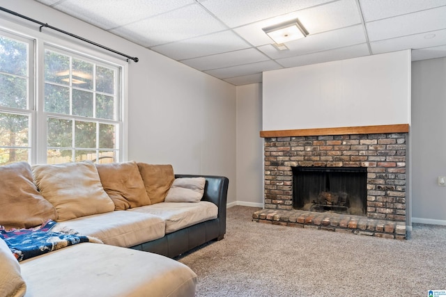 carpeted living room featuring a paneled ceiling and a brick fireplace