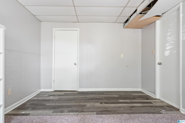 spare room with dark hardwood / wood-style flooring and a drop ceiling