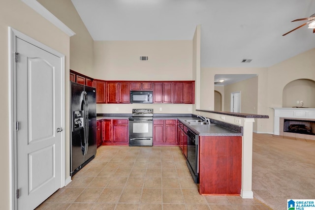 kitchen with black appliances, ceiling fan, light colored carpet, kitchen peninsula, and a tiled fireplace