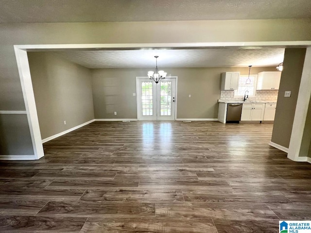 unfurnished dining area featuring a chandelier, a textured ceiling, sink, and dark hardwood / wood-style flooring