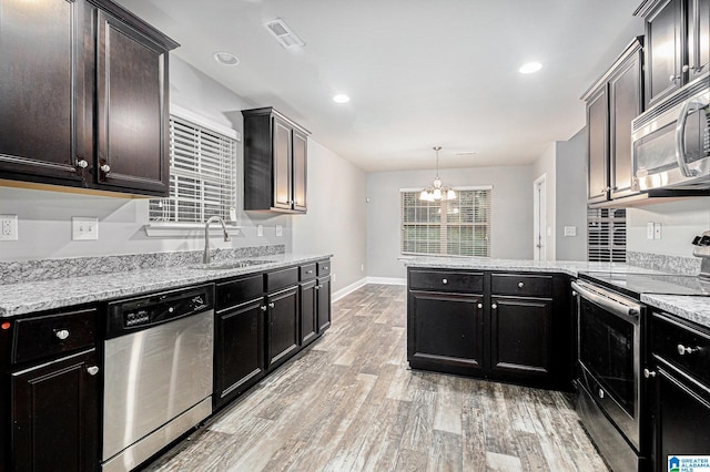 kitchen featuring appliances with stainless steel finishes, light wood-type flooring, sink, pendant lighting, and a chandelier