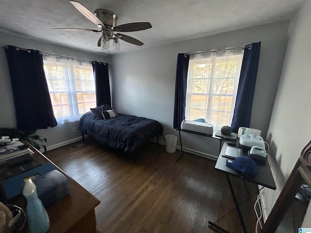 bedroom featuring ceiling fan, dark hardwood / wood-style flooring, and multiple windows