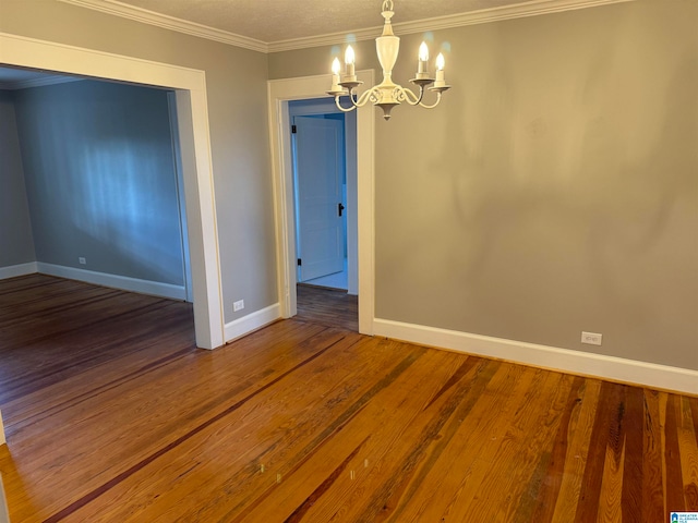 empty room featuring hardwood / wood-style floors, a chandelier, and ornamental molding