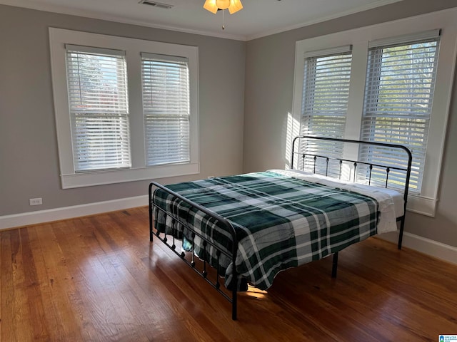 bedroom with hardwood / wood-style floors, ceiling fan, and crown molding