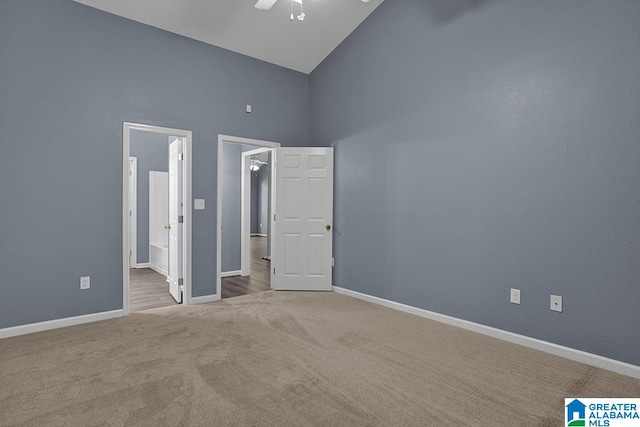 unfurnished bedroom with high vaulted ceiling, light colored carpet, ceiling fan, and connected bathroom