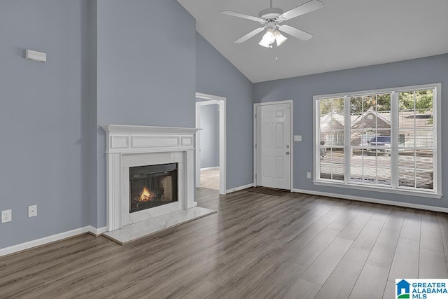 unfurnished living room with a high end fireplace, hardwood / wood-style floors, ceiling fan, and high vaulted ceiling