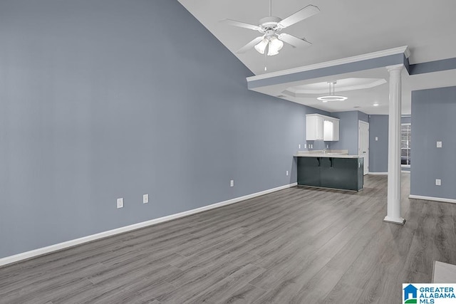 unfurnished living room with light hardwood / wood-style floors, ceiling fan, ornate columns, and ornamental molding