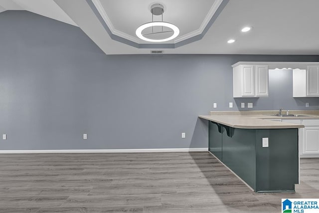 kitchen with ornamental molding, white cabinetry, decorative light fixtures, a kitchen breakfast bar, and light hardwood / wood-style flooring