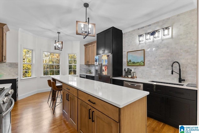 kitchen featuring a kitchen island, appliances with stainless steel finishes, sink, and light hardwood / wood-style floors