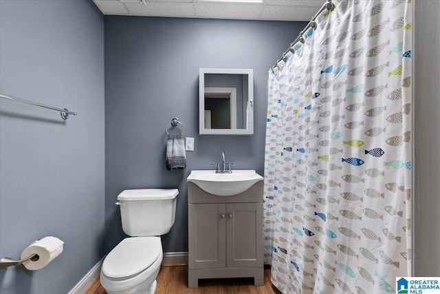 bathroom with vanity, a shower with shower curtain, hardwood / wood-style flooring, toilet, and a drop ceiling