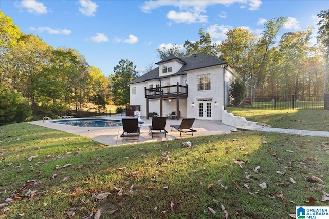 rear view of house featuring a lawn, a balcony, a fenced in pool, and french doors