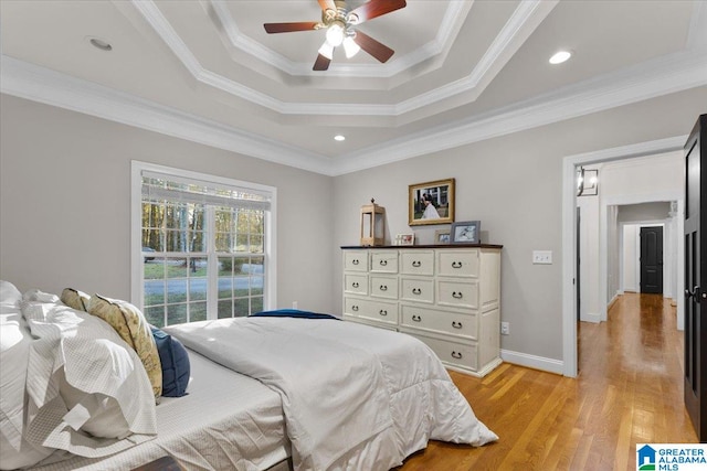 bedroom with light wood-type flooring, a raised ceiling, ceiling fan, and crown molding